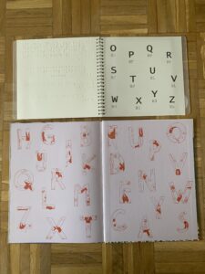 The last pages of both versions of the book. The last pages of the standard version in the bottom half of the picture are identical to the first two pages, showing random capital letters whereas the braille version again only shows the letters on the last page. The pre last page is a normal braille book page with the last bit of text.